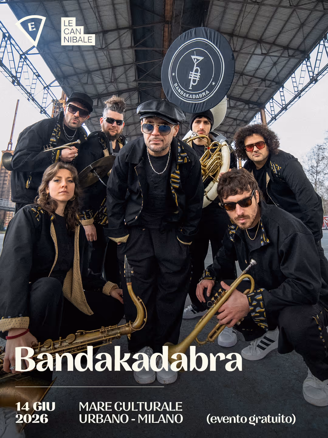 Bandakababra brass band posing under a metal roof, holding instruments, event in Milan 14 June 2026.