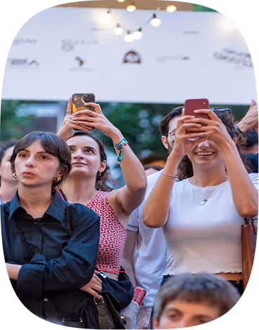 Group of people at an event, some smiling and taking photos with smartphones.